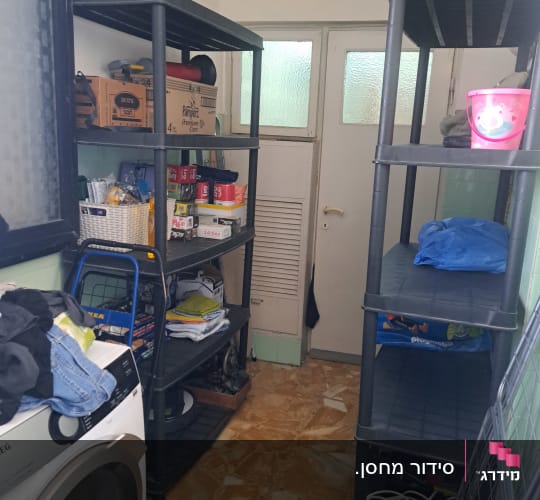 מדפים עם קופסאות, מגבות ומוצרי ניקוי בחדר שירות